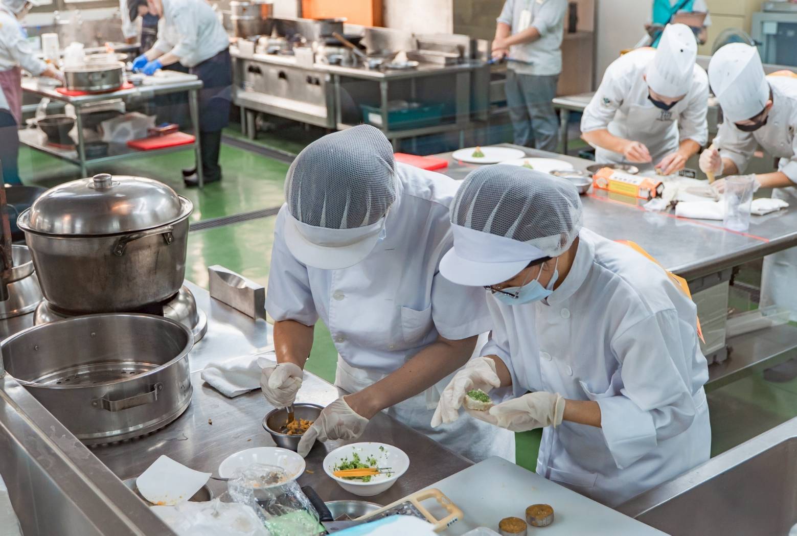 2-參賽選手專注投入料理比賽，運用在地食材與質地調整技巧創作軟食料理，從色、香、味展現健康與美味兼具的餐桌新風貌