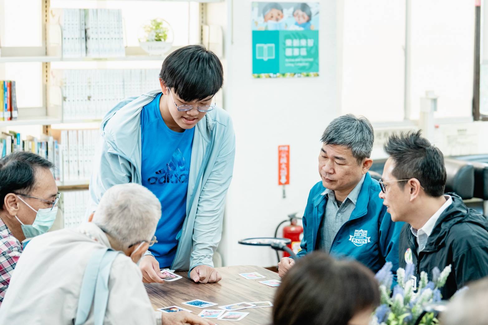 高雄中學桌遊社學生利用「樂齡樂智專區」桌遊資源帶領長者一同玩桌遊