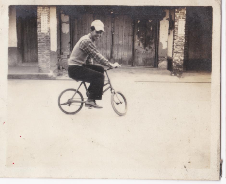 16 日光照相館創辦人張仁葵於民居前騎小腳踏車